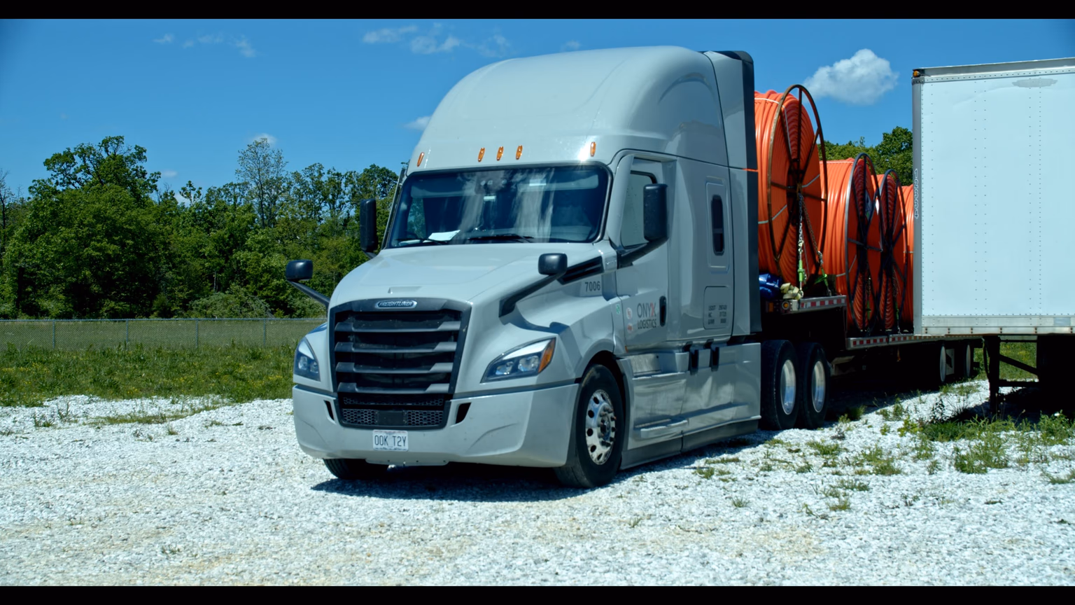 An Onyx Logistics Freightliner Cascadia tractor at the Strafford, Missouri yard, treeline behind the trailer.